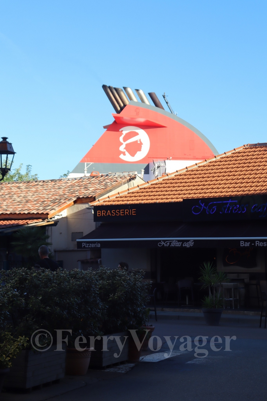 The iconic Superfast funnel, albeit now shorn of its wingtips, towers over waterfront restaurants in Propriano.